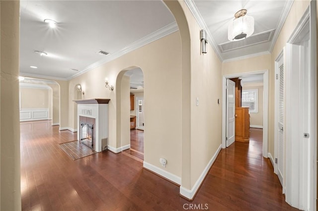 corridor featuring visible vents, wood finished floors, arched walkways, crown molding, and baseboards