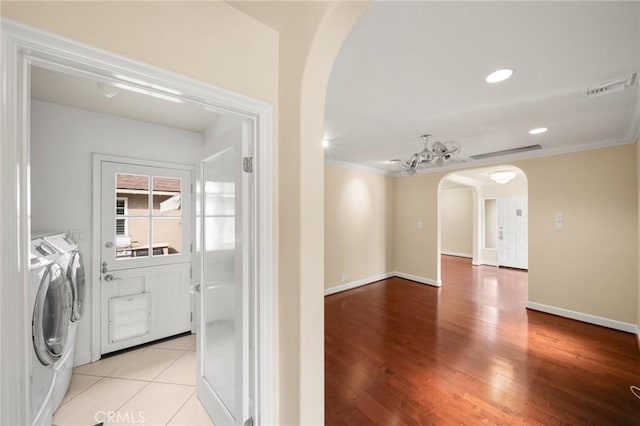 interior space featuring light wood-type flooring, washing machine and dryer, arched walkways, crown molding, and laundry area