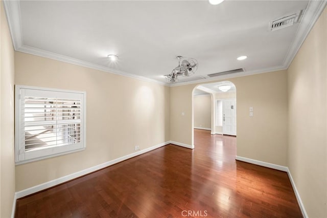 empty room with visible vents, arched walkways, wood finished floors, and ornamental molding