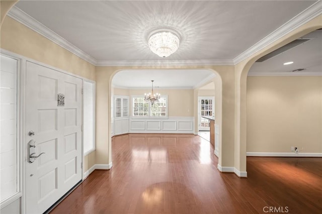 entrance foyer featuring an inviting chandelier, crown molding, wood finished floors, and arched walkways