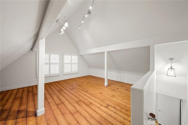 additional living space with hardwood / wood-style floors, vaulted ceiling, and baseboards