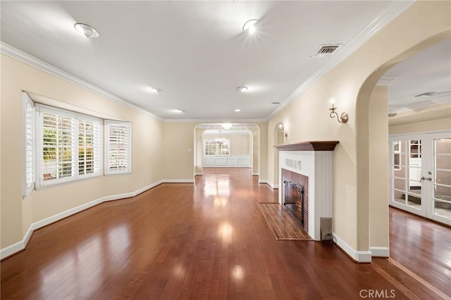 unfurnished living room featuring arched walkways, visible vents, and crown molding