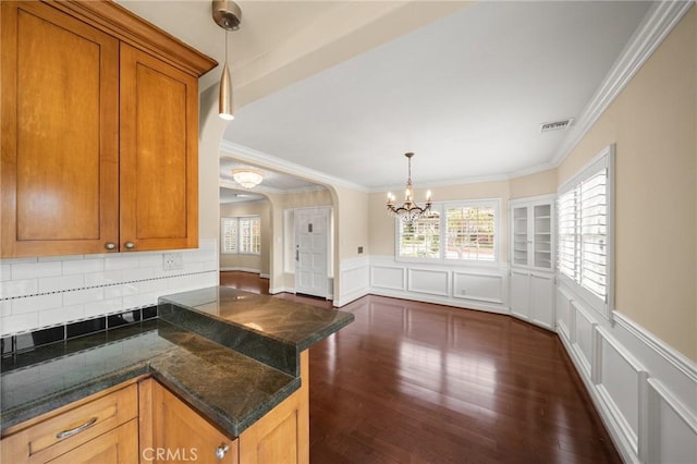 kitchen with decorative light fixtures, visible vents, a peninsula, and dark wood finished floors