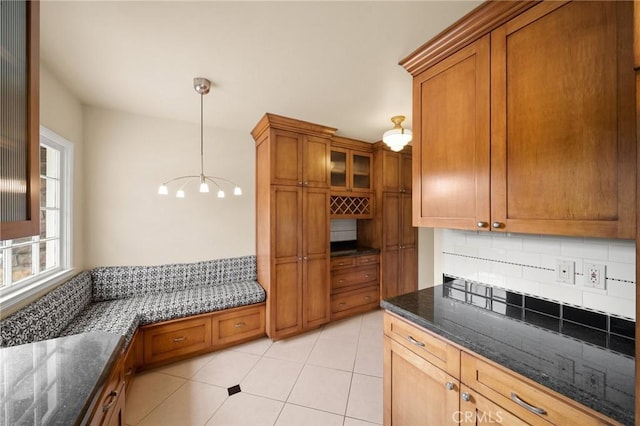 kitchen featuring brown cabinetry, backsplash, and dark stone counters