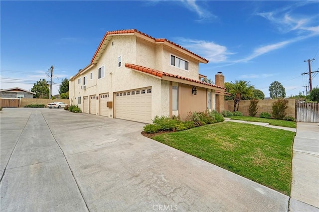 view of property exterior featuring stucco siding, a tile roof, fence, a yard, and a garage