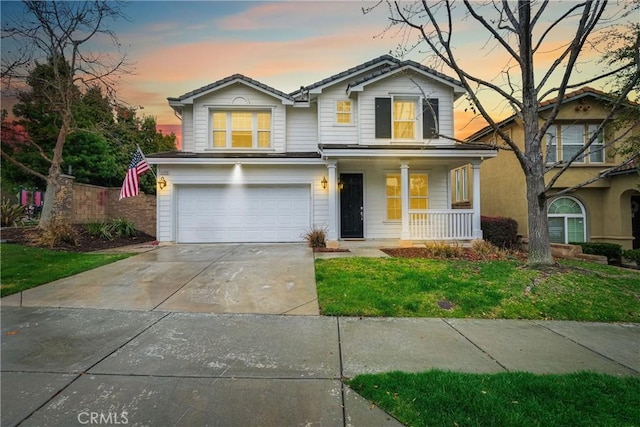 traditional-style house featuring a porch, concrete driveway, a yard, and an attached garage