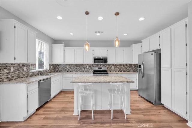 kitchen with visible vents, white cabinets, appliances with stainless steel finishes, and a center island