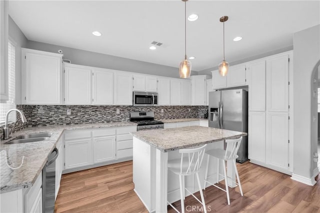 kitchen featuring visible vents, arched walkways, a sink, appliances with stainless steel finishes, and white cabinetry