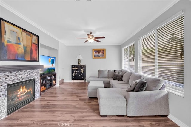 living room featuring baseboards, wood finished floors, ornamental molding, and a fireplace