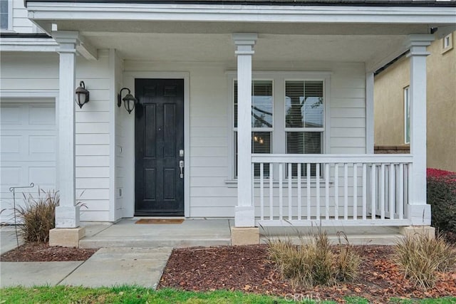 doorway to property featuring a porch and a garage