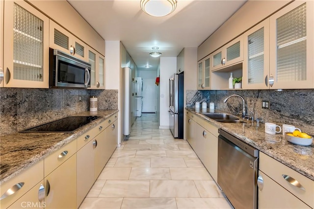 kitchen with light stone counters, backsplash, appliances with stainless steel finishes, and a sink