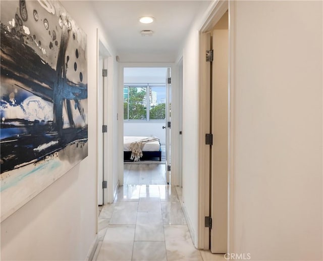 hallway with light tile patterned floors and baseboards