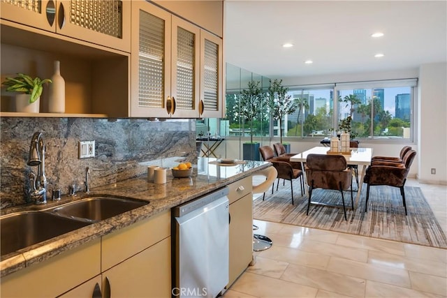 kitchen with dishwasher, light stone countertops, backsplash, and a sink