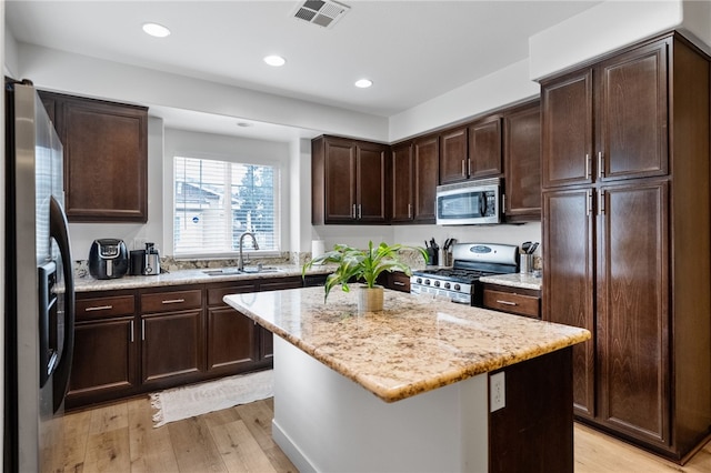 kitchen featuring visible vents, stainless steel appliances, light wood finished floors, and a sink