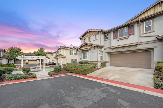 view of property with a residential view, stucco siding, driveway, and an attached garage