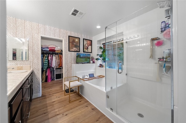 full bathroom with visible vents, a stall shower, hardwood / wood-style flooring, wallpapered walls, and vanity