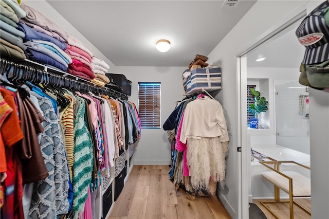 walk in closet with wood finished floors