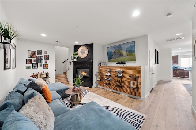 living area with recessed lighting, visible vents, a large fireplace, and light wood-style floors