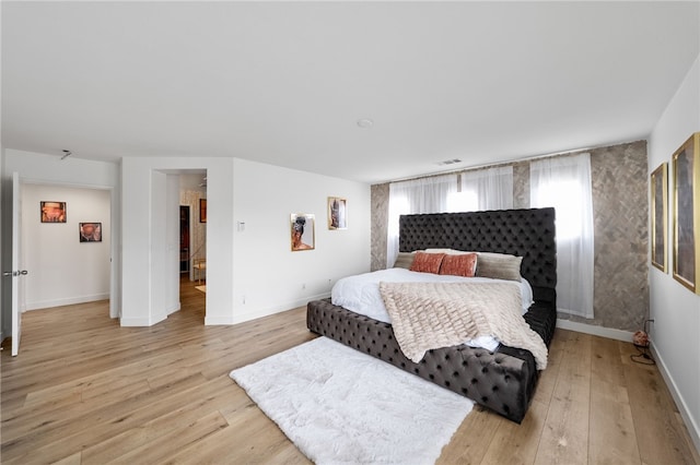 bedroom with light wood-type flooring, baseboards, and visible vents