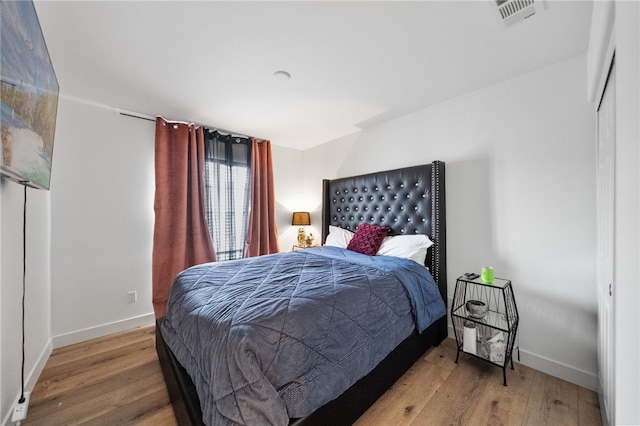 bedroom featuring light wood finished floors, visible vents, and baseboards