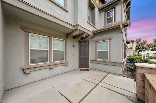 view of exterior entry featuring a patio area and stucco siding