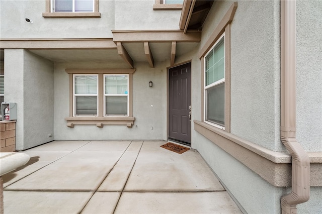 entrance to property with stucco siding and a patio area