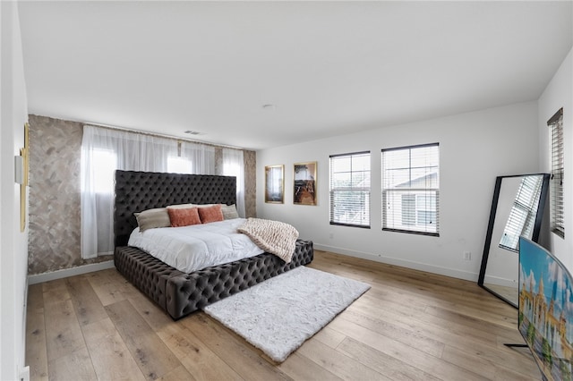 bedroom with light wood-style flooring, visible vents, and baseboards