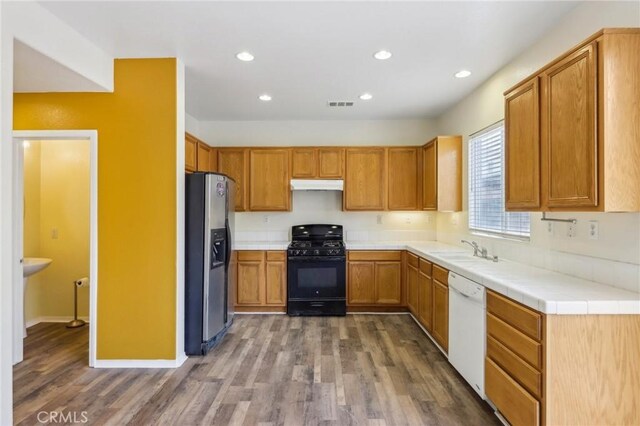 kitchen featuring under cabinet range hood, a sink, stainless steel fridge, white dishwasher, and black range with gas stovetop