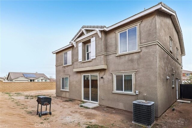 rear view of property featuring stucco siding, cooling unit, and fence