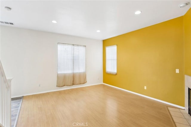 unfurnished room featuring light wood-type flooring, visible vents, recessed lighting, a fireplace, and baseboards