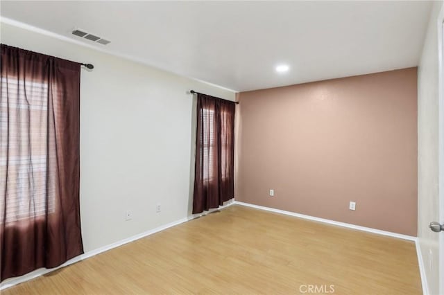 unfurnished room with light wood finished floors, visible vents, and baseboards