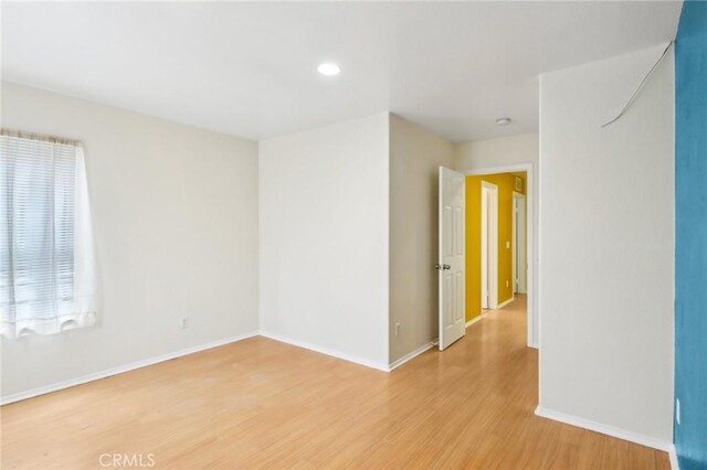 spare room featuring recessed lighting, baseboards, and light wood-style floors