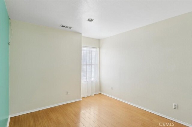 unfurnished room featuring visible vents, light wood-type flooring, and baseboards