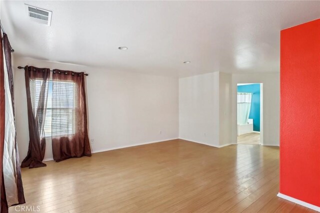 spare room with baseboards, visible vents, and wood-type flooring