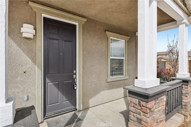 property entrance with stucco siding and a porch