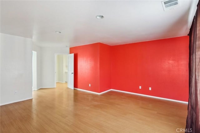 spare room featuring visible vents, baseboards, and wood finished floors