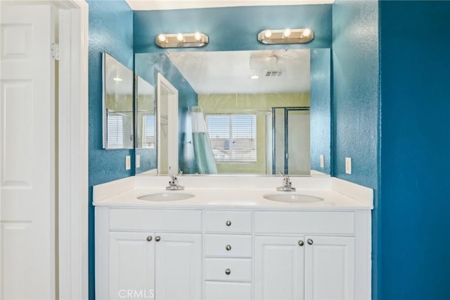 full bath featuring a shower stall, double vanity, visible vents, and a sink