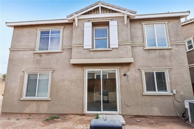 rear view of property with a tiled roof, cooling unit, and stucco siding