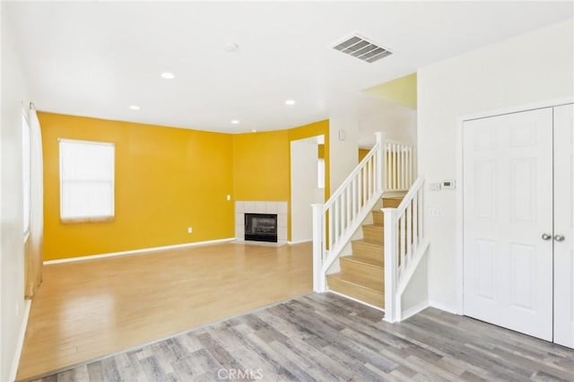 living area featuring visible vents, wood finished floors, recessed lighting, stairway, and a tile fireplace