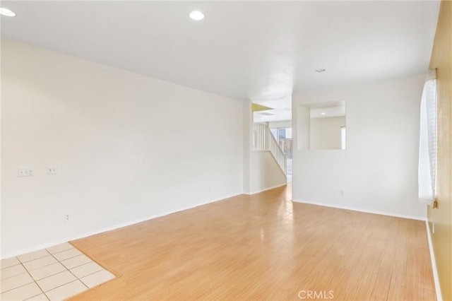 unfurnished room featuring stairway, recessed lighting, baseboards, and wood finished floors