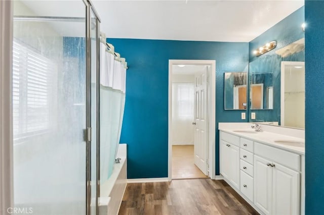 full bathroom featuring a washtub, a shower with door, a sink, wood finished floors, and double vanity