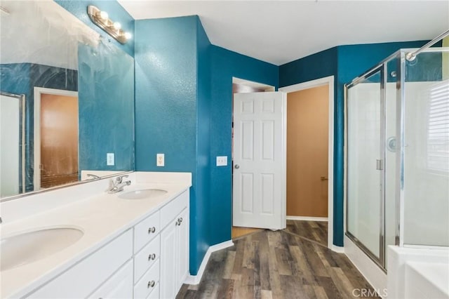 bathroom featuring a sink, wood finished floors, a stall shower, and double vanity