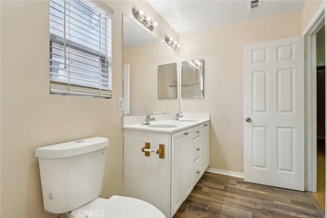 bathroom with a sink, visible vents, toilet, and wood finished floors