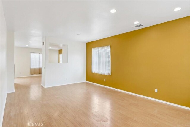 spare room featuring light wood-style floors, visible vents, and baseboards