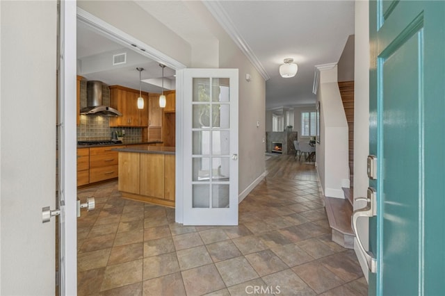 foyer entrance featuring visible vents, baseboards, a warm lit fireplace, and crown molding