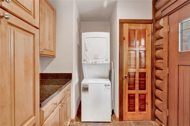 laundry area featuring log walls, cabinet space, and stacked washer and clothes dryer