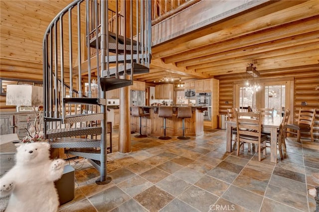 staircase featuring beam ceiling, a notable chandelier, log walls, and a towering ceiling