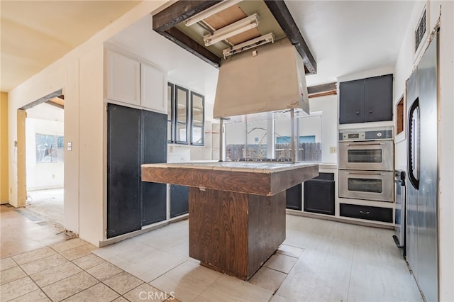 kitchen with glass insert cabinets, a kitchen island, appliances with stainless steel finishes, and white cabinets