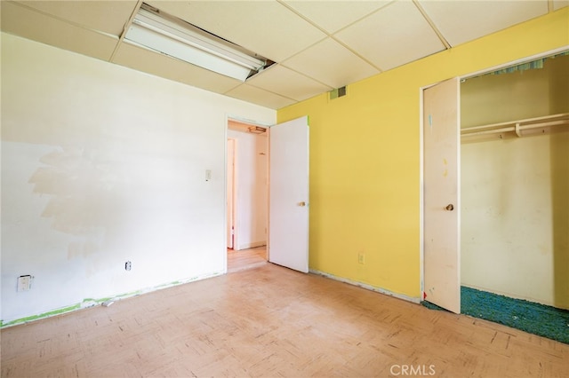 unfurnished bedroom featuring a closet, visible vents, and a paneled ceiling