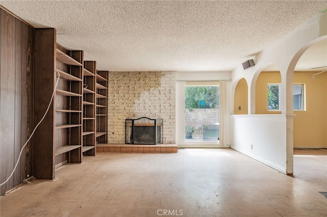 unfurnished living room featuring a fireplace, a textured ceiling, and baseboards